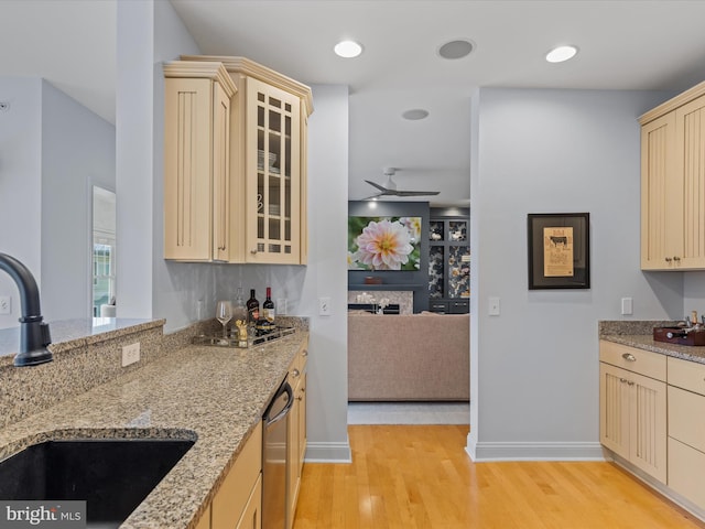 kitchen featuring sink, light hardwood / wood-style flooring, light stone countertops, ceiling fan, and stainless steel dishwasher