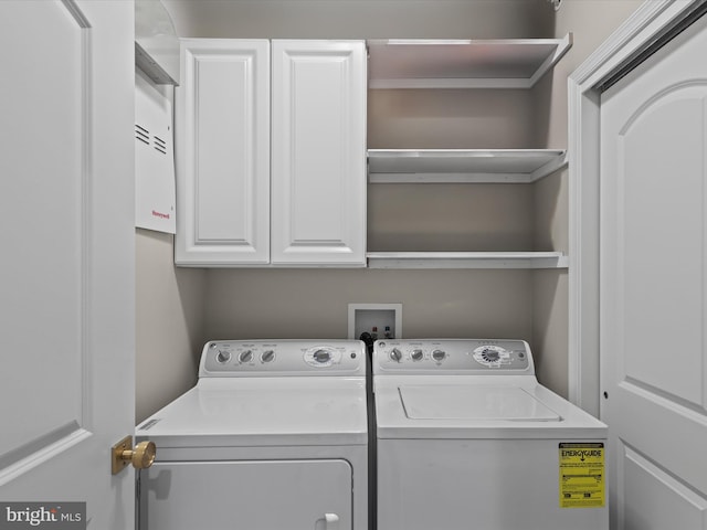 clothes washing area featuring washing machine and dryer and cabinets