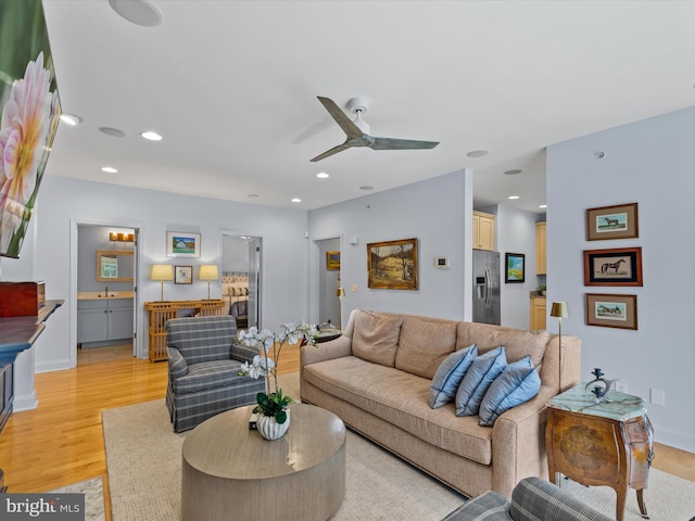 living room with light wood-type flooring, sink, and ceiling fan