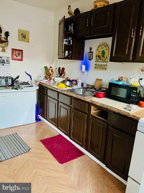 kitchen featuring dark brown cabinets, white range oven, and light parquet floors