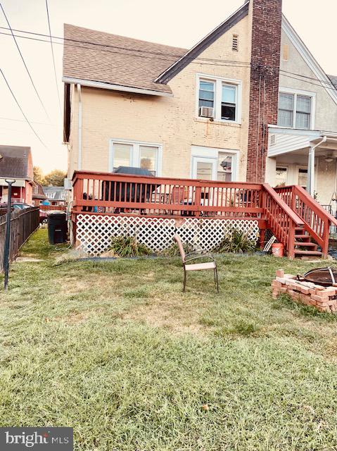 rear view of house with a wooden deck and a lawn