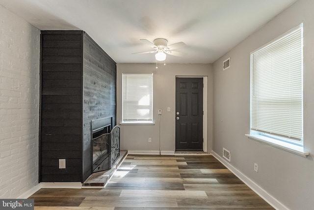 entrance foyer with ceiling fan, hardwood / wood-style flooring, and a large fireplace