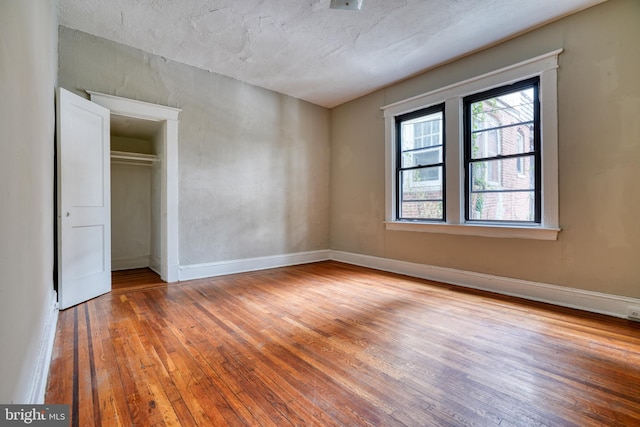 unfurnished bedroom featuring hardwood / wood-style flooring, a closet, and a textured ceiling