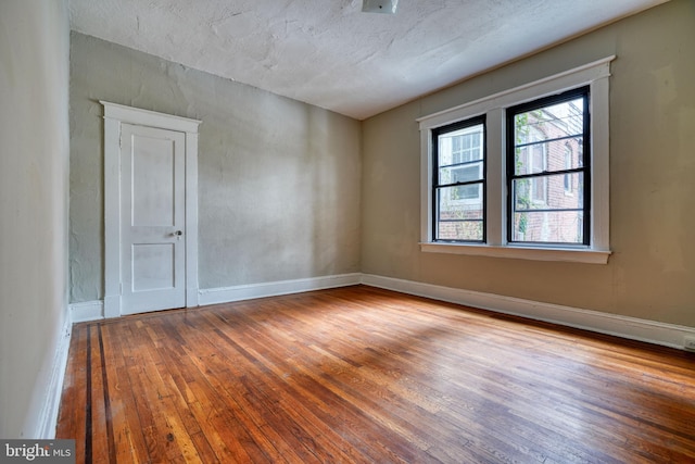 spare room with a textured ceiling and hardwood / wood-style floors