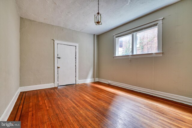 empty room with a textured ceiling and hardwood / wood-style floors