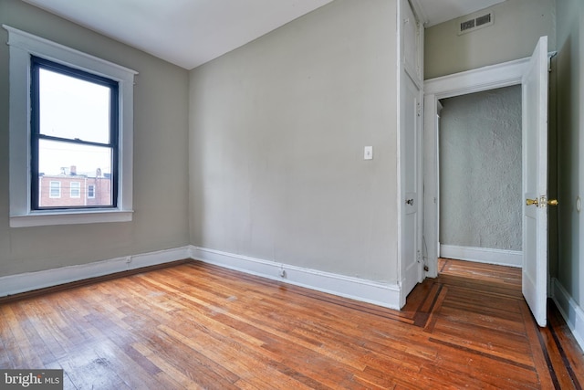 empty room featuring baseboards, visible vents, and wood-type flooring