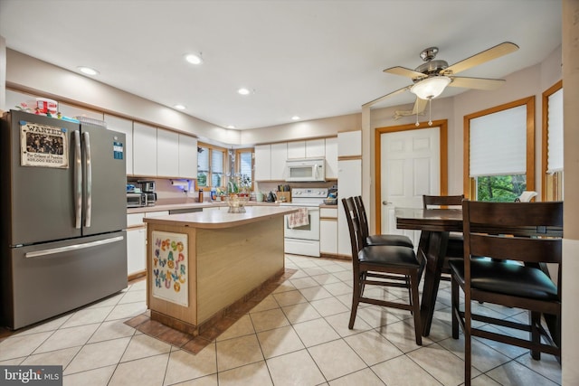 kitchen featuring white cabinetry, a kitchen island, white appliances, light tile patterned floors, and ceiling fan