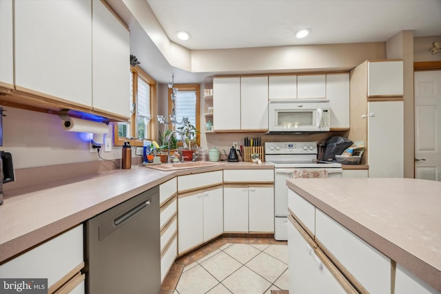 kitchen featuring light tile patterned flooring, sink, white appliances, and white cabinetry