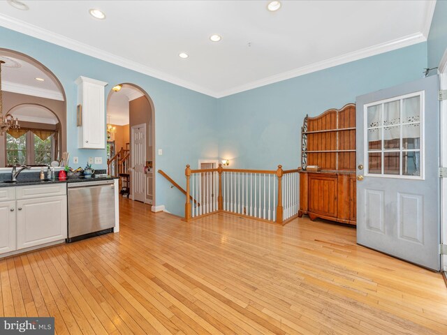 kitchen with white cabinets, crown molding, light hardwood / wood-style flooring, stainless steel dishwasher, and sink