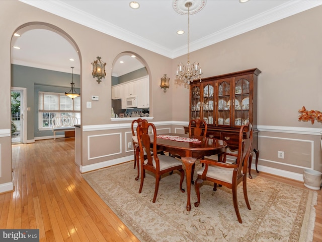 dining room with ornamental molding, light hardwood / wood-style flooring, and a chandelier