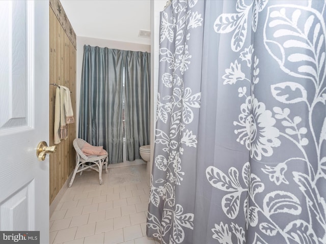 bathroom with wooden walls, tile patterned floors, and toilet