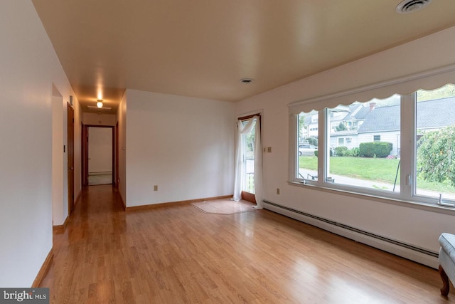 unfurnished room with baseboard heating, light hardwood / wood-style floors, and a wealth of natural light