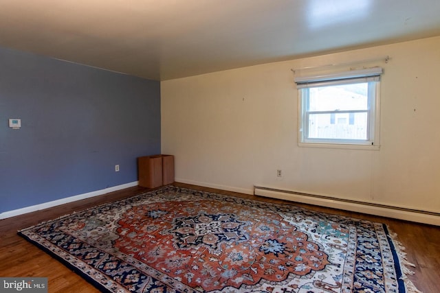 empty room featuring a baseboard heating unit and hardwood / wood-style floors