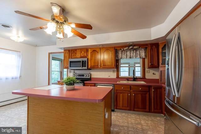 kitchen featuring a center island, sink, decorative backsplash, appliances with stainless steel finishes, and ceiling fan