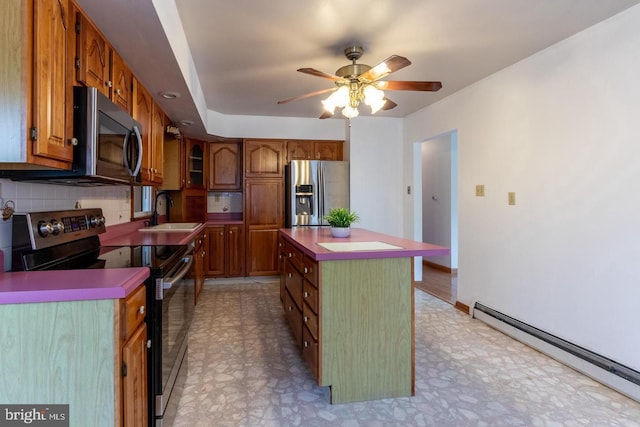 kitchen with ceiling fan, sink, tasteful backsplash, a kitchen island, and appliances with stainless steel finishes