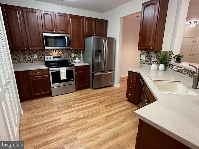 kitchen featuring light hardwood / wood-style floors, stainless steel appliances, sink, and tasteful backsplash