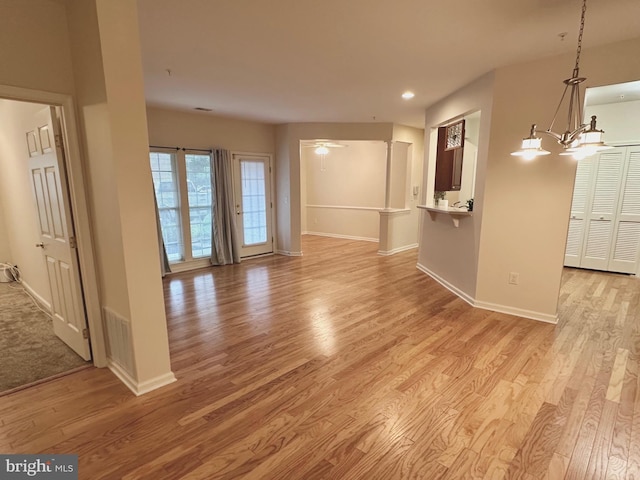 empty room with light hardwood / wood-style flooring and a notable chandelier