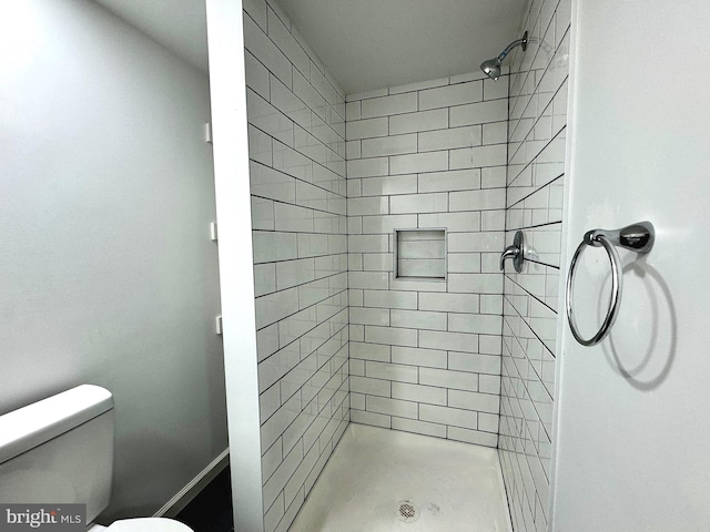 bathroom with a tile shower and toilet