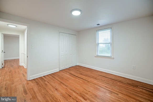 unfurnished bedroom with light hardwood / wood-style flooring and a closet