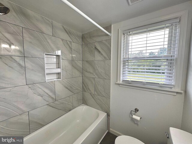 bathroom with tiled shower / bath and toilet