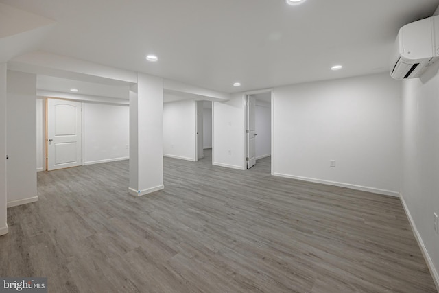 basement with an AC wall unit and hardwood / wood-style flooring