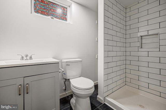 bathroom with tiled shower, vanity, and toilet