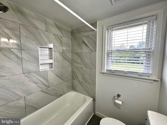 bathroom featuring toilet and tiled shower / bath