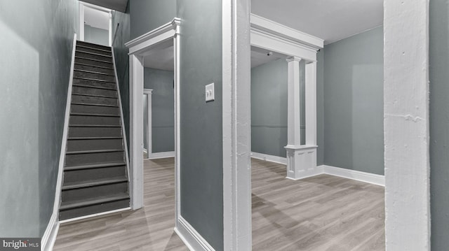 staircase with decorative columns and hardwood / wood-style floors