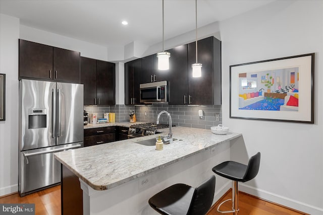 kitchen with hanging light fixtures, kitchen peninsula, a kitchen bar, and stainless steel appliances