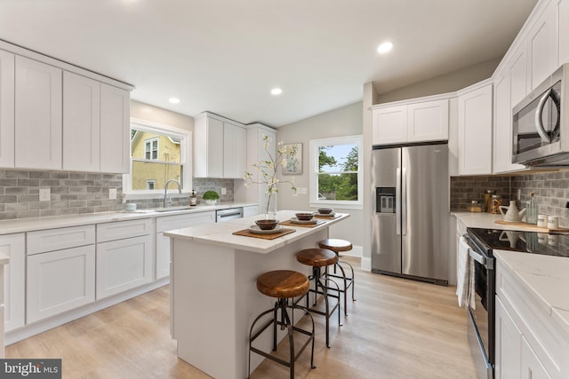 kitchen featuring stainless steel appliances, white cabinets, and a center island