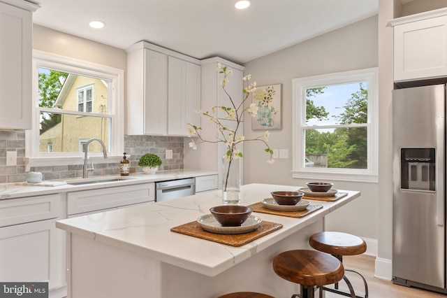 kitchen featuring a wealth of natural light, appliances with stainless steel finishes, sink, and white cabinetry