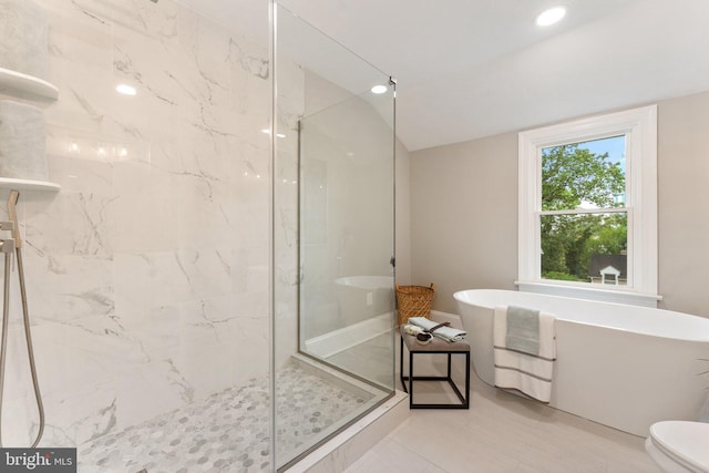 bathroom featuring shower with separate bathtub and toilet