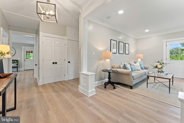 living room featuring a notable chandelier, crown molding, and light hardwood / wood-style floors