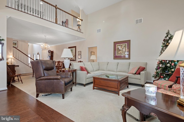 living room with crown molding, light hardwood / wood-style flooring, a notable chandelier, and high vaulted ceiling