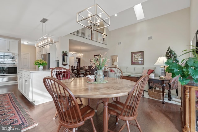 dining room with a skylight, dark hardwood / wood-style flooring, and a high ceiling