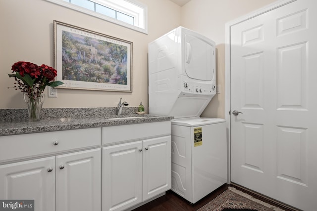 laundry area featuring cabinets, dark hardwood / wood-style floors, stacked washer / dryer, and sink