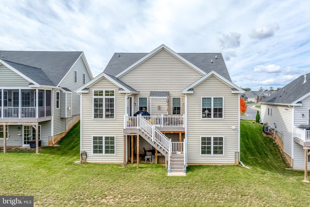 back of house featuring a yard, a sunroom, and a wooden deck