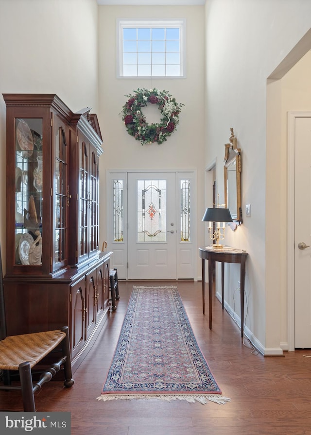 entrance foyer with a healthy amount of sunlight, dark wood-type flooring, and a high ceiling