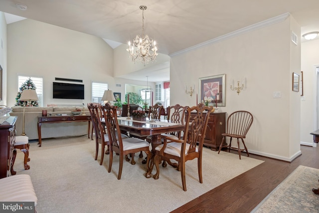 dining area featuring ornamental molding, a notable chandelier, hardwood / wood-style floors, and high vaulted ceiling