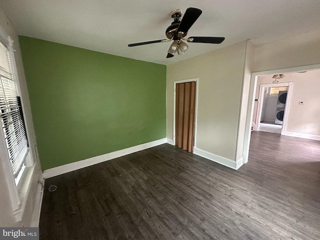 unfurnished bedroom with stacked washing maching and dryer, ceiling fan, and dark wood-type flooring