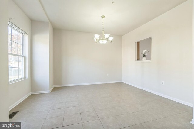 tiled empty room featuring a notable chandelier