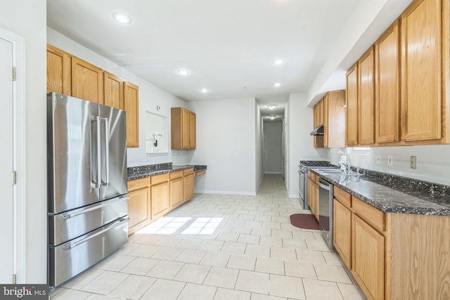 kitchen featuring sink, appliances with stainless steel finishes, light tile patterned flooring, and dark stone counters