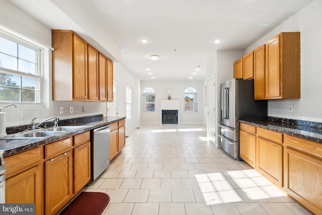 kitchen with sink, appliances with stainless steel finishes, light tile patterned floors, and dark stone counters