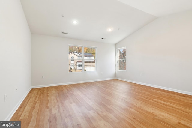 empty room with light hardwood / wood-style flooring and vaulted ceiling