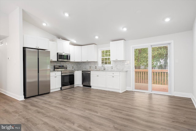 kitchen with white cabinetry, stainless steel appliances, light wood-type flooring, lofted ceiling, and sink