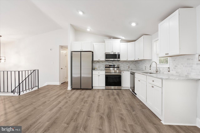 kitchen featuring white cabinets, vaulted ceiling, appliances with stainless steel finishes, and sink