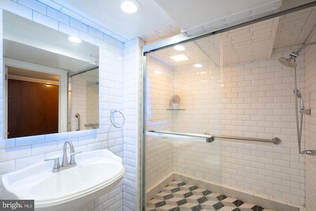 bathroom featuring tile walls, backsplash, an enclosed shower, and sink