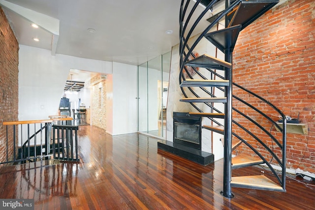 staircase with hardwood / wood-style floors and brick wall