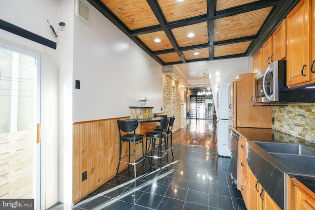 kitchen featuring stainless steel appliances, dark hardwood / wood-style floors, wooden ceiling, a breakfast bar, and a towering ceiling