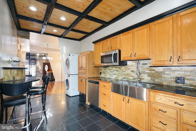 kitchen featuring decorative backsplash, wood ceiling, stainless steel appliances, stacked washer / dryer, and sink